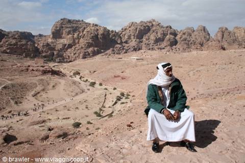 Bedouin man in keffiyeh sitting on red rocks of Petra