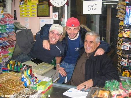 Three smiling men hugging behind the counter of a souvenir shop