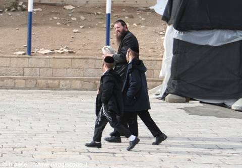 Orthodox Jewish man with two boys walking on the stone pavement of the Western Wall