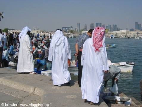 Men in white thobes at Doha's fishing harbour, boats and skyscrapers behind