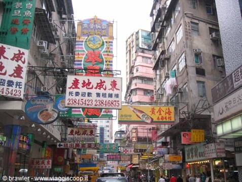 Crowded Chinese neon signs line a narrow Hong Kong street between tall buildings