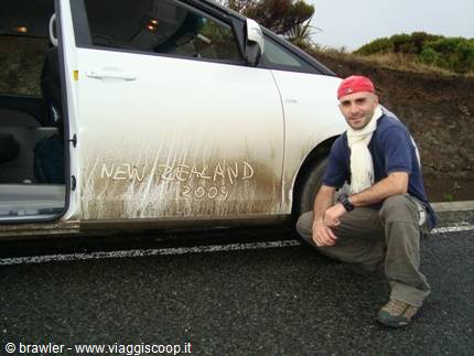 Traveler next to a mud-covered car with New Zealand 2009 written