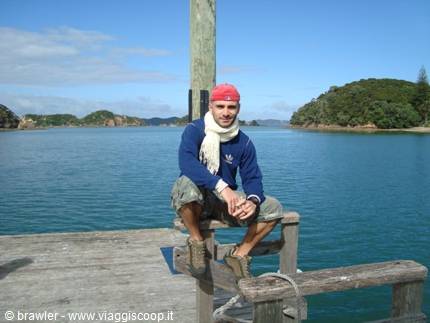 Traveler sitting on a wooden pier, turquoise sea and green islands behind