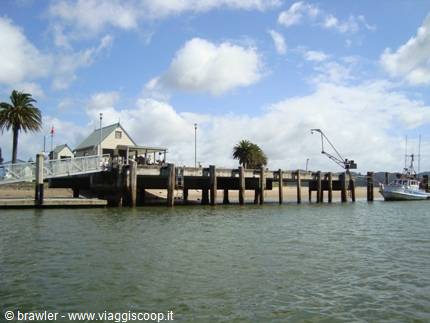 Wooden pier on stilts over the sea, moored boat, palm trees and clouds