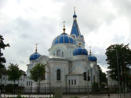 White Orthodox church with blue golden domes under cloudy sky