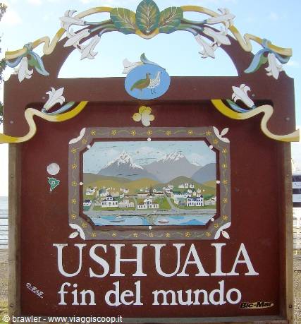 Painted wooden Ushuaia sign with mountains and flowers under a blue sky