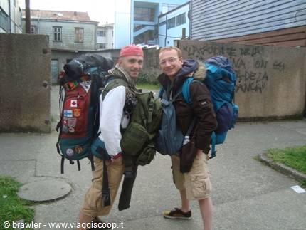 Two smiling backpackers with large hiking packs on a city street