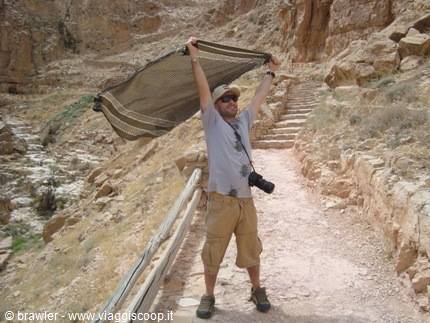 Tourist with camera raises a keffiyeh over rock-cut steps, Petra