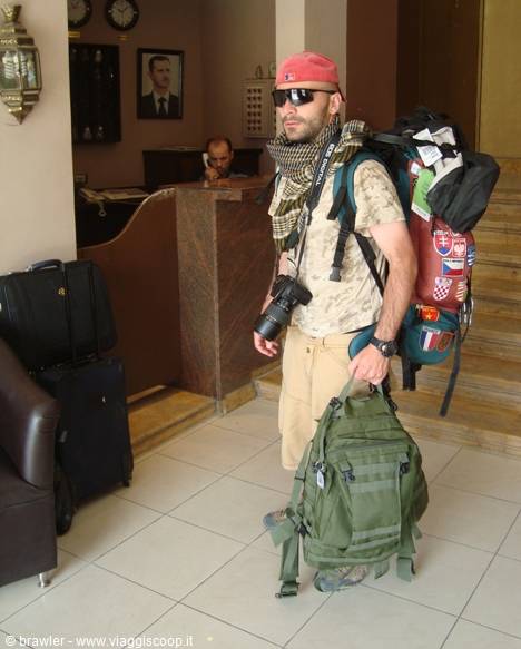 Traveler with huge backpack, camera and green duffel bag in a hotel lobby