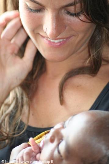 Smiling mother holding a sleeping newborn baby in soft natural light