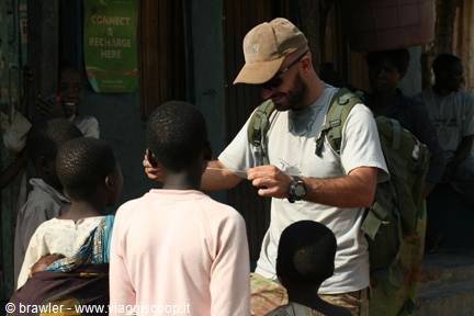 Backpacker with green backpack shows something to children in an African village