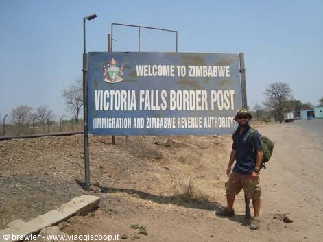 Backpacker posing next to the Victoria Falls border post sign, Zimbabwe