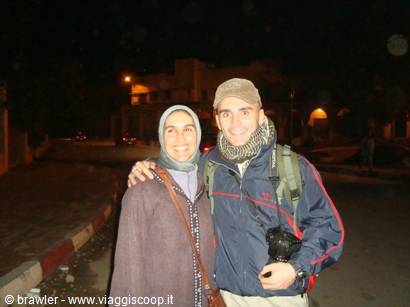 Couple with backpack and camera on a street at night