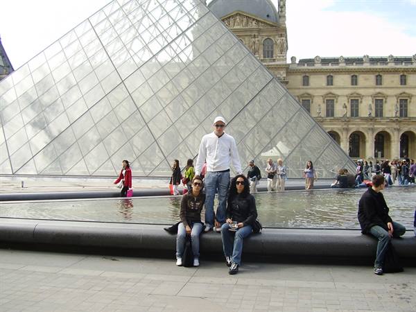 Tourists by the fountain in front of the Louvre glass pyramid