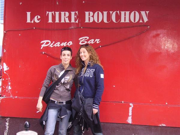 Two women in front of the red wall of Le Tire Bouchon piano bar