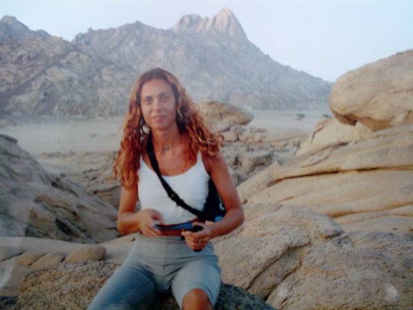 Woman with curly hair sitting on granite rocks in the desert