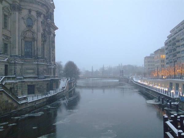 Snow-covered Berlin Cathedral along the Spree, falling snow and riverside lights