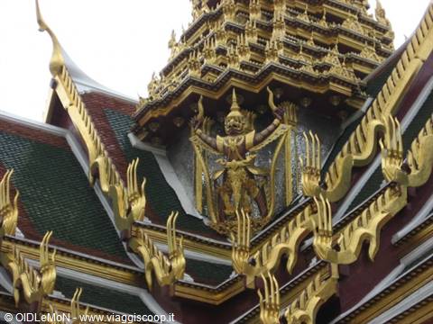 Golden demon figure on green and gold roofs of Bangkok's Grand Palace