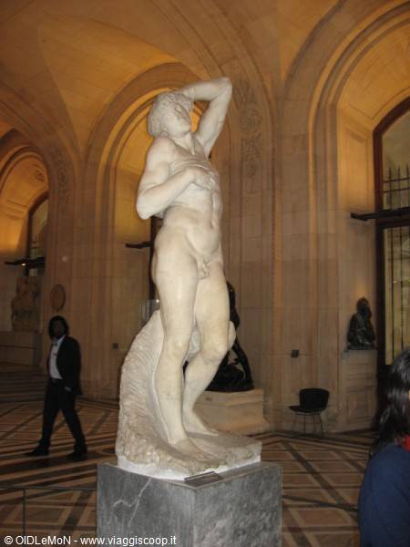 Marble male statue at the Louvre Museum, Paris, warm light under vaulted halls