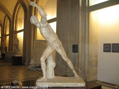 Ancient marble statue of a striding fighting man, vaulted gallery lit warmly