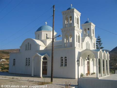 White church with blue domes and bell towers under clear sky, Greek island