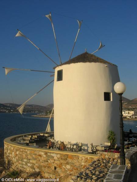 Old white windmill with canvas sails, harbor terrace in Parikia