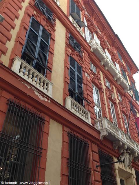 Baroque facade in red and yellow with white marble balconies and dark shutters