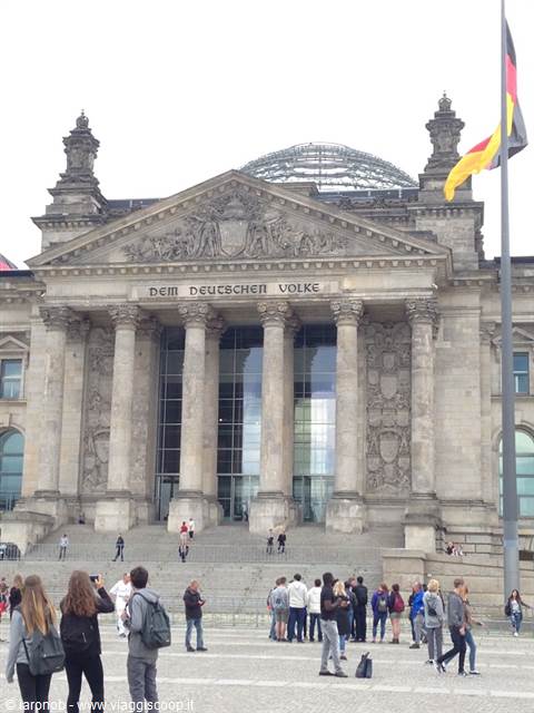 Tourists in front of Berlin's Reichstag, stone columns and German flag waving