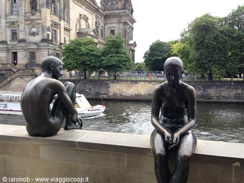 Two nude bronze statues sitting along the Spree river in Berlin
