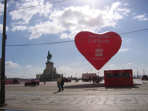 Red Amate Lisboa heart balloon at Praça do Comércio, equestrian statue, people in afternoon light