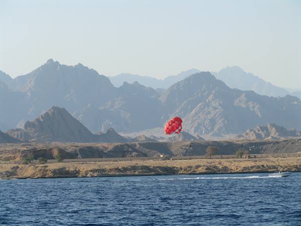 Red parasail towed by a speedboat on the Red Sea before desert mountains