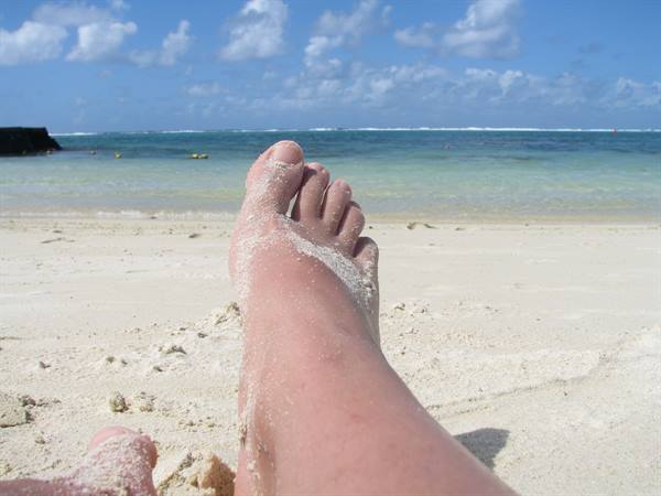 Sandy foot stretched out on white sand before turquoise sea