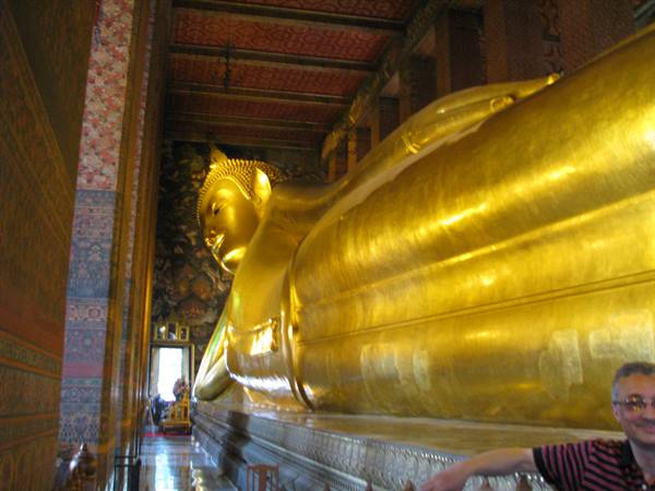 Golden reclining Buddha statue inside Wat Pho temple, tourists nearby