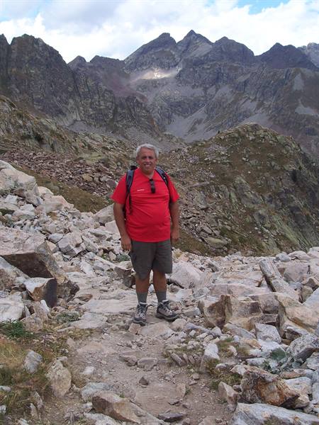 Hiker with backpack on rocky trail among alpine peaks