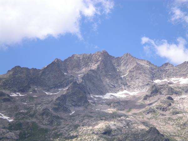Rocky peaks with leftover snow under blue sky and white clouds