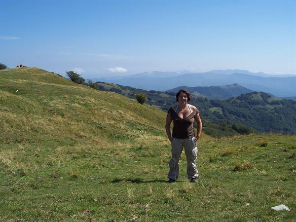 Woman standing on a mountain meadow with blue ridges behind