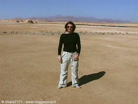 Woman in black sweater and light jeans standing on desert sand