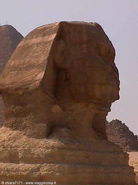 The Great Sphinx of Giza in sandstone, pyramids rising behind under bright sun