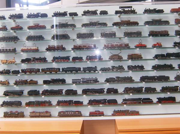 Display case with miniature locomotives and wagons on illuminated glass shelves