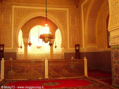 Meknes mausoleum interior: glowing chandeliers, carved stucco, zellige tiles and wooden screens