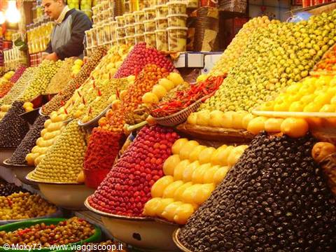 Vendor among mounds of olives and dried fruit in Marrakech souk