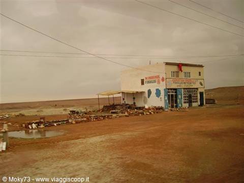 Roadside restaurant on a rocky desert road, grey sky and red earth