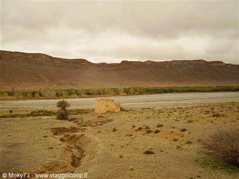 mud-brick kasbah along the Ziz river with palms and arid mountains