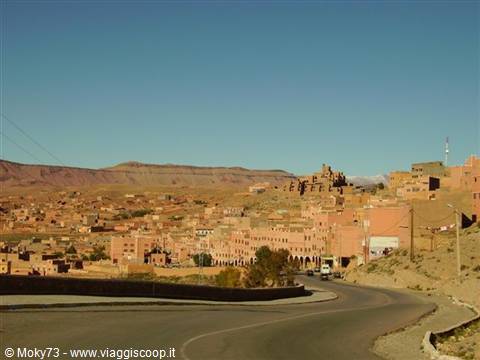 Ouarzazate town, red earthen buildings among mountains under blue sky