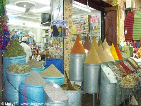 Spice market in Marrakech: colorful cones in blue sacks and tin cans