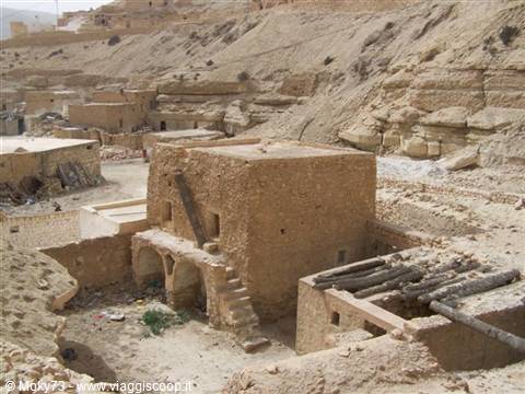 Mud-brick houses with arches among arid rocky hills, Berber village