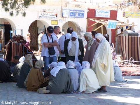 Douz market: men in white robes gathered seated on the ground