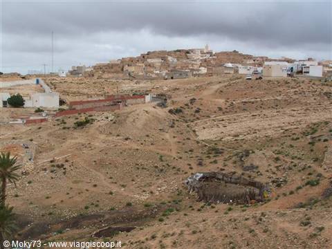 Village of concrete houses on arid hillside under cloudy sky