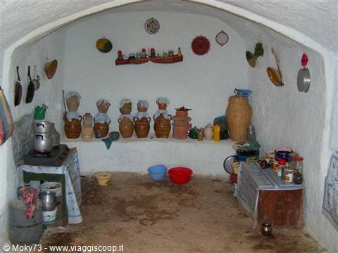Rural house interior with terracotta amphorae, pots and blankets hanging on white walls