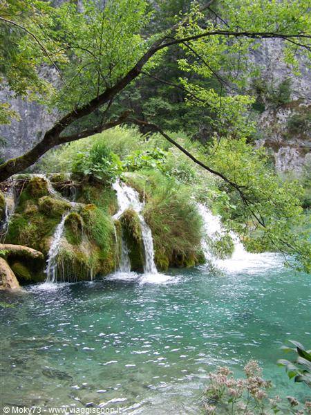 Small waterfalls flow over green moss into turquoise waters at Plitvice